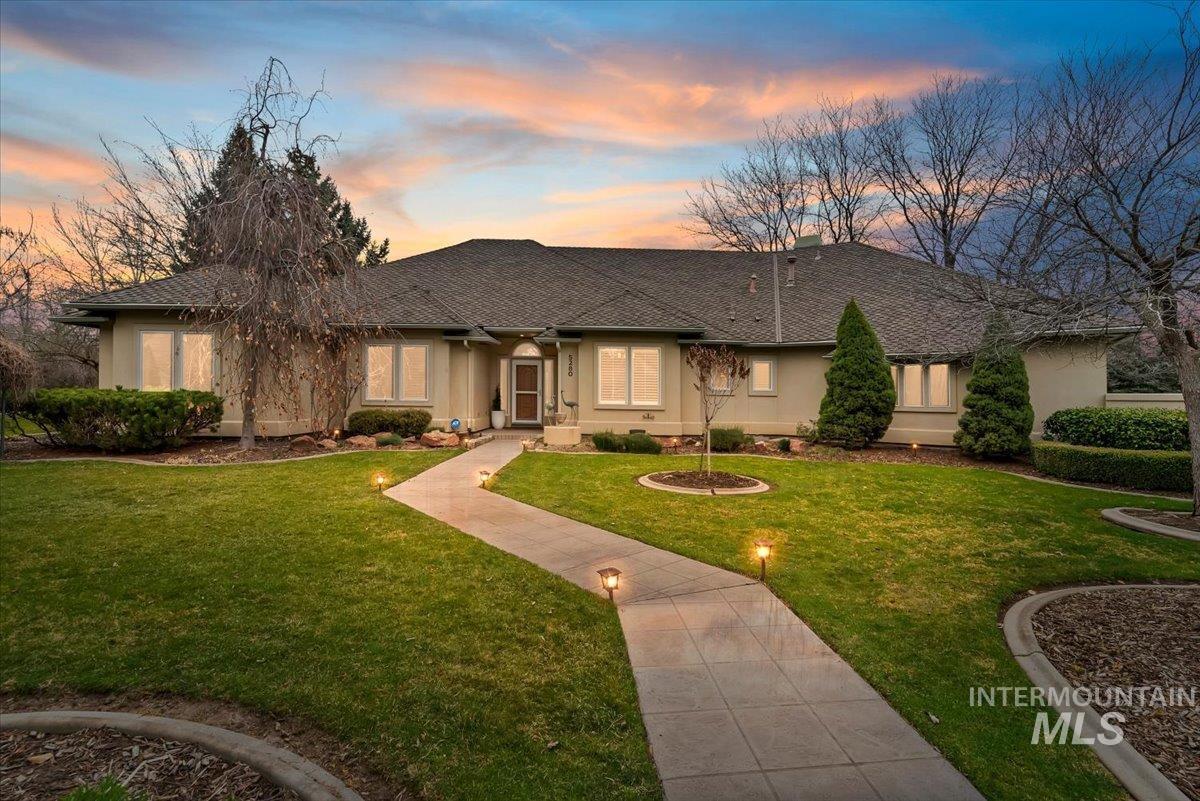 Ranch-style house with stucco siding, a yard, and roof with shingles