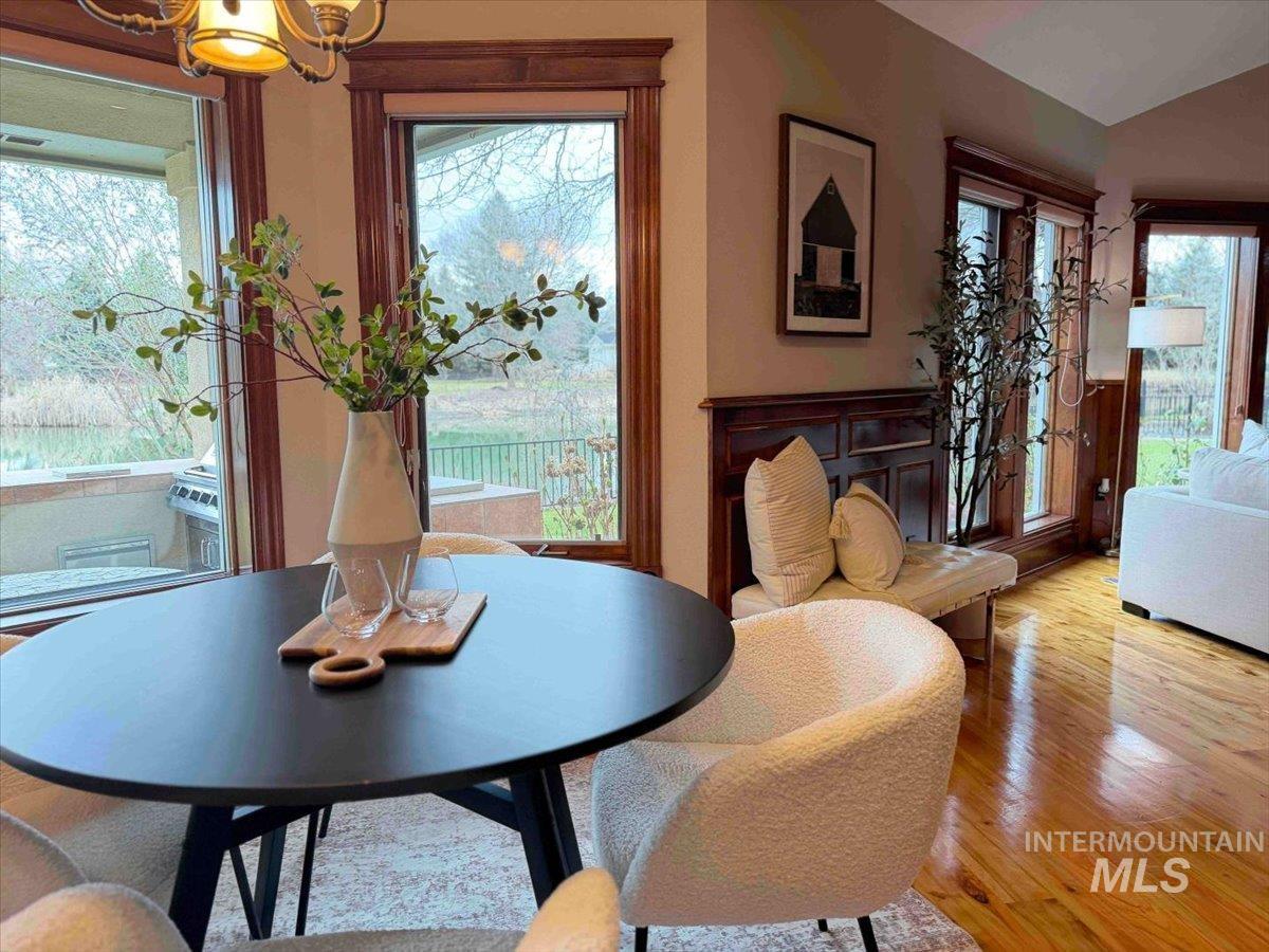 Dining space with light wood-style floors, lofted ceiling, and a chandelier