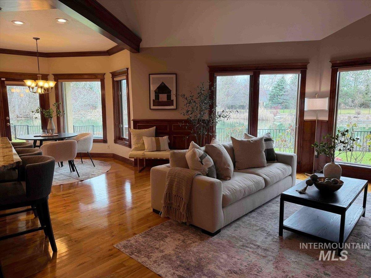 Living area with wood finished floors, hanging lights, and crown molding
