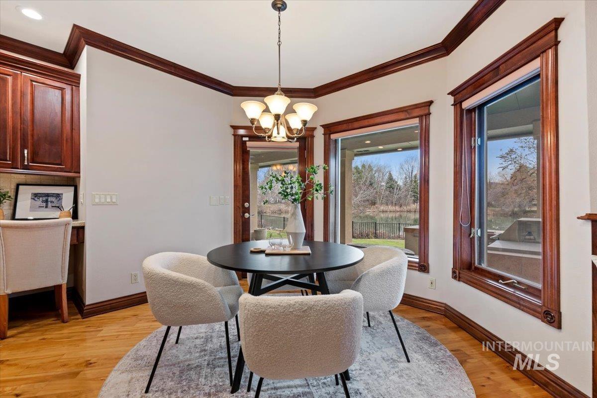Dining area featuring light wood-type flooring, hanging lights, and ornamental molding