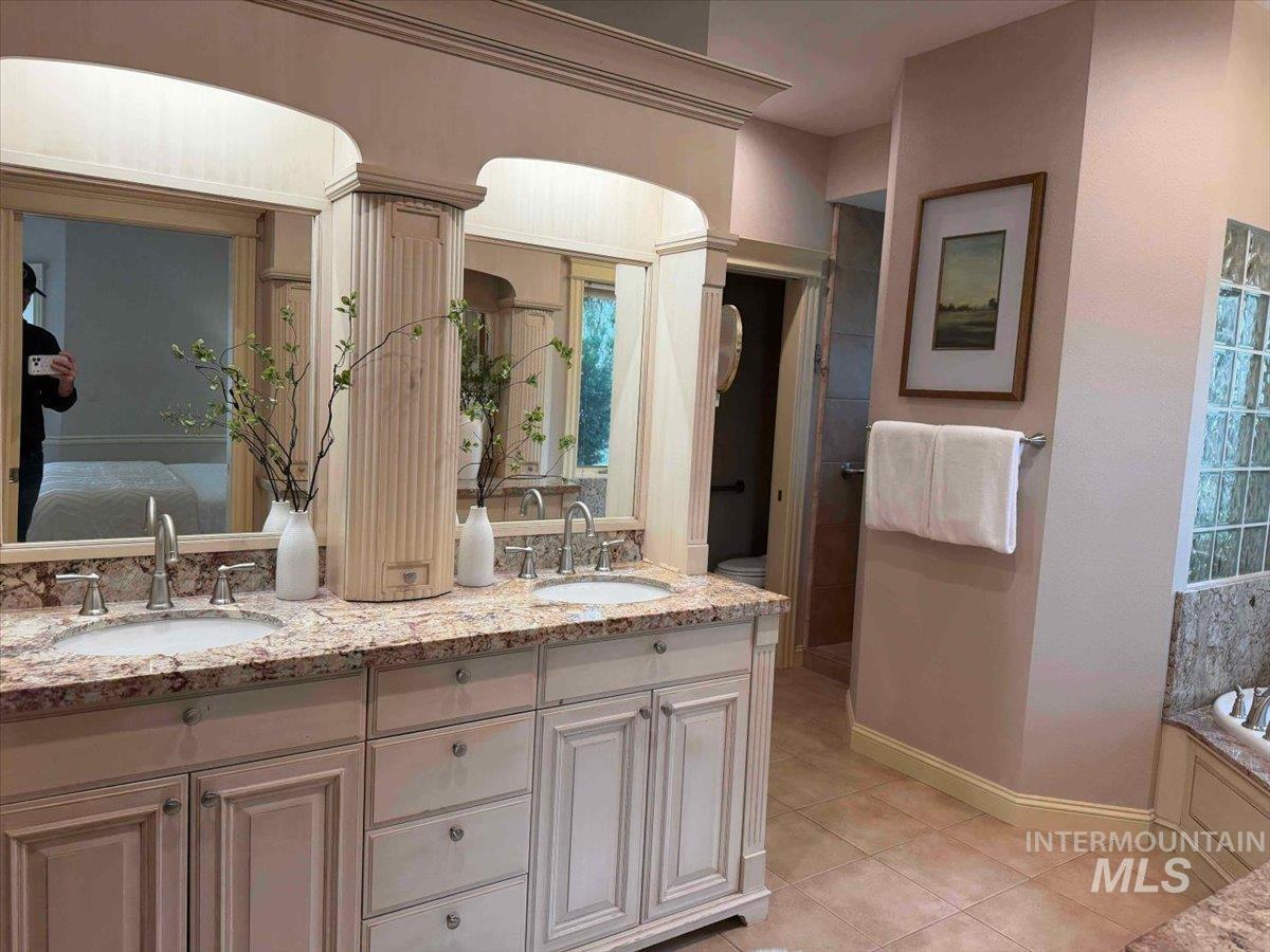 Bathroom with double vanity, light tile patterned flooring, a bath, and ensuite bathroom