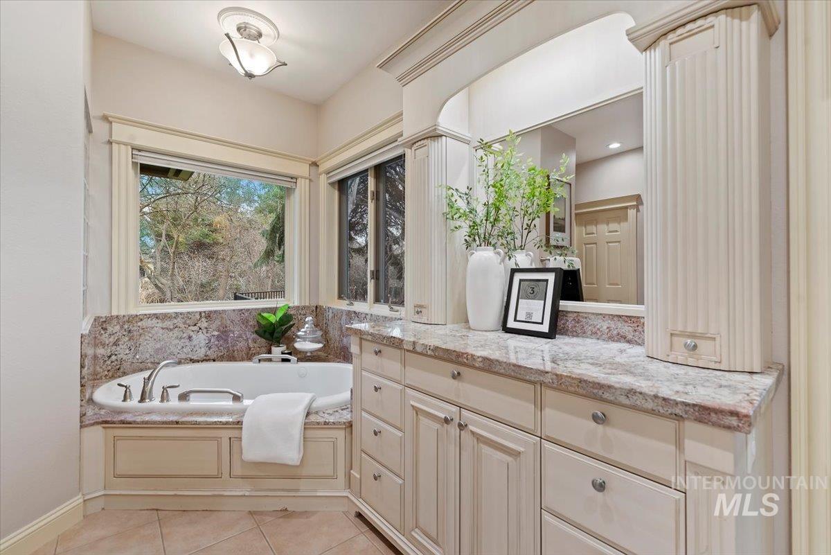 Bathroom featuring vanity, a bath, and light tile patterned floors
