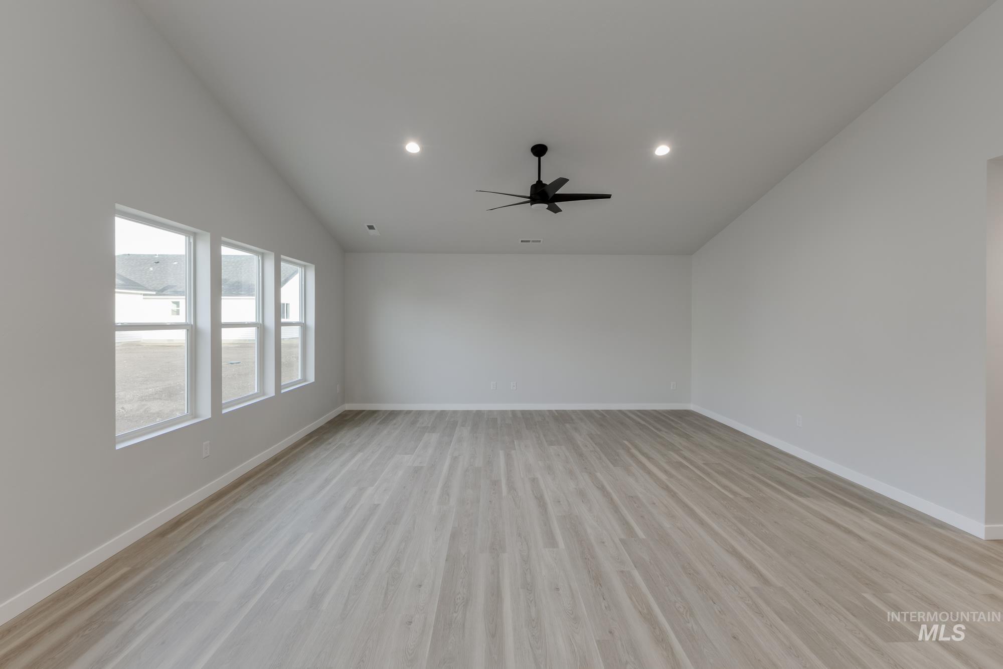 Empty room with light wood finished floors, lofted ceiling, recessed lighting, and ceiling fan