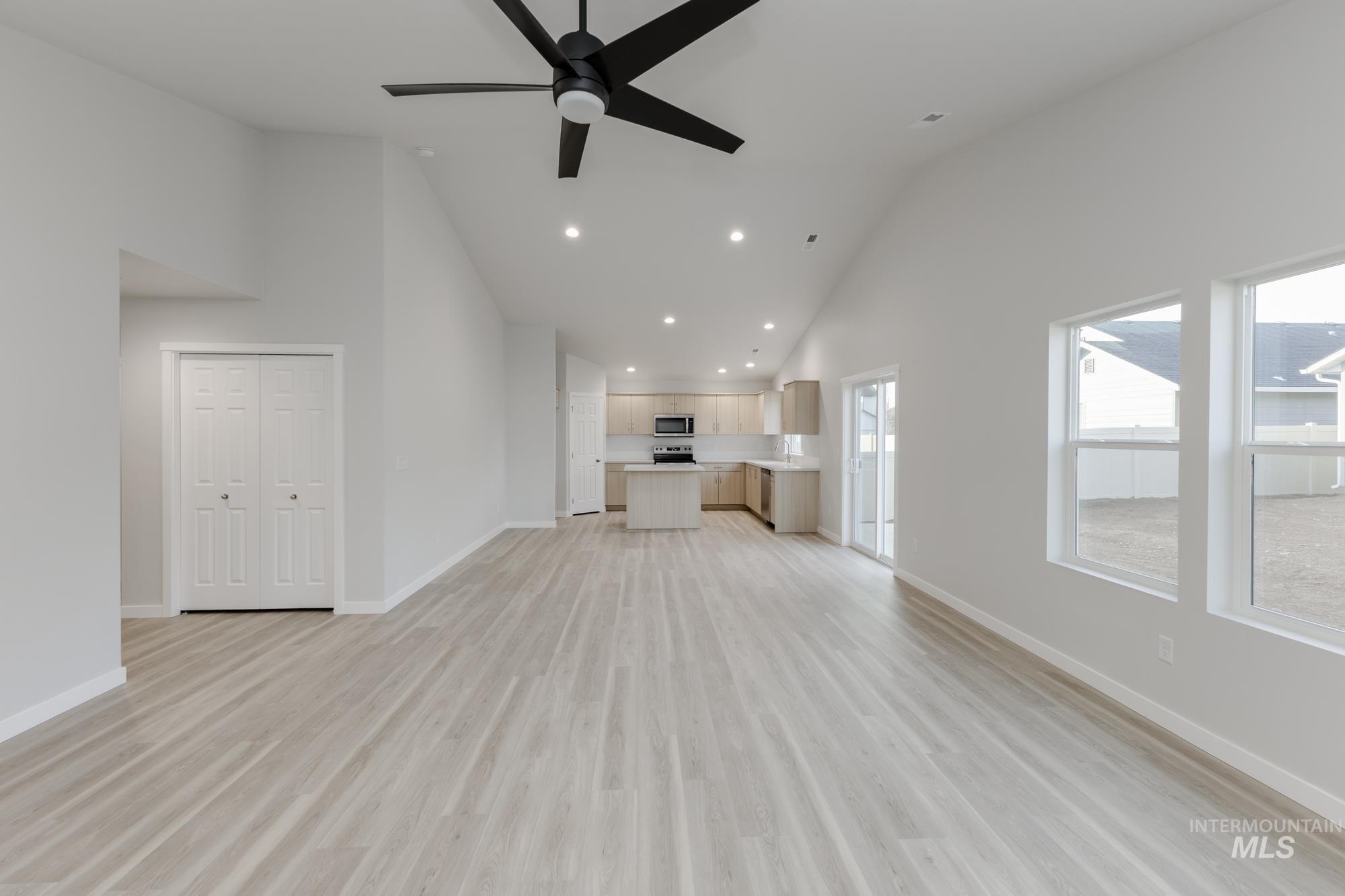 Unfurnished living room with high vaulted ceiling, a ceiling fan, light wood finished floors, and recessed lighting