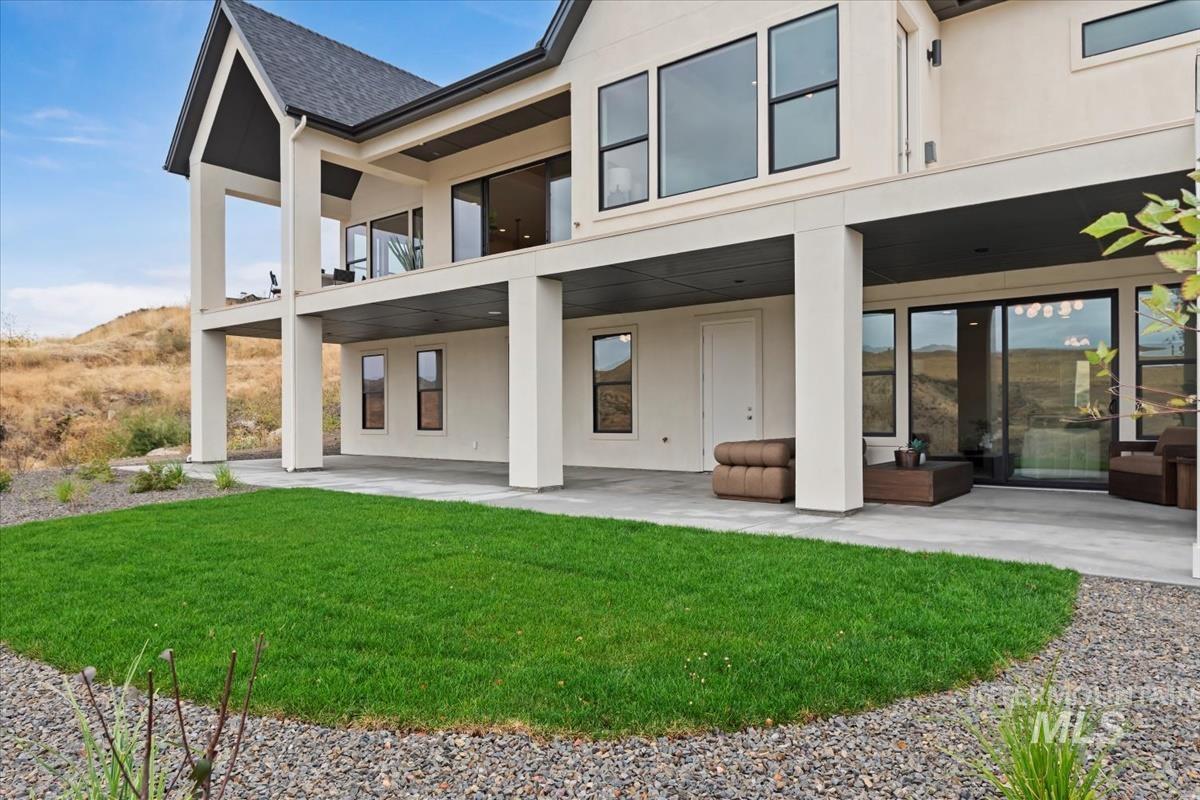 Back of property with stucco siding, a patio area, and a lawn