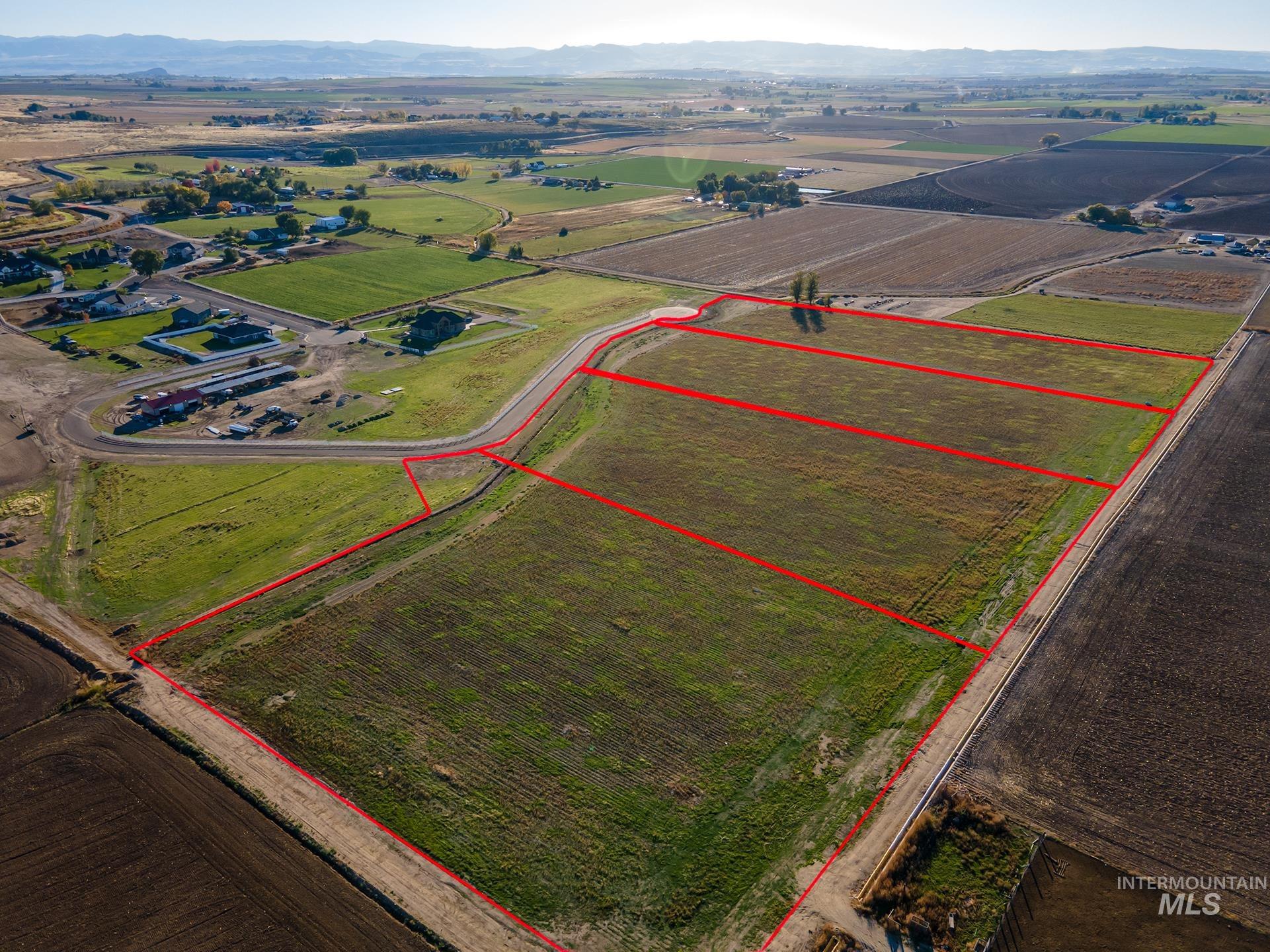 Aerial view of sparsely populated area featuring property boundaries highlighted, mountains, and rows of crops