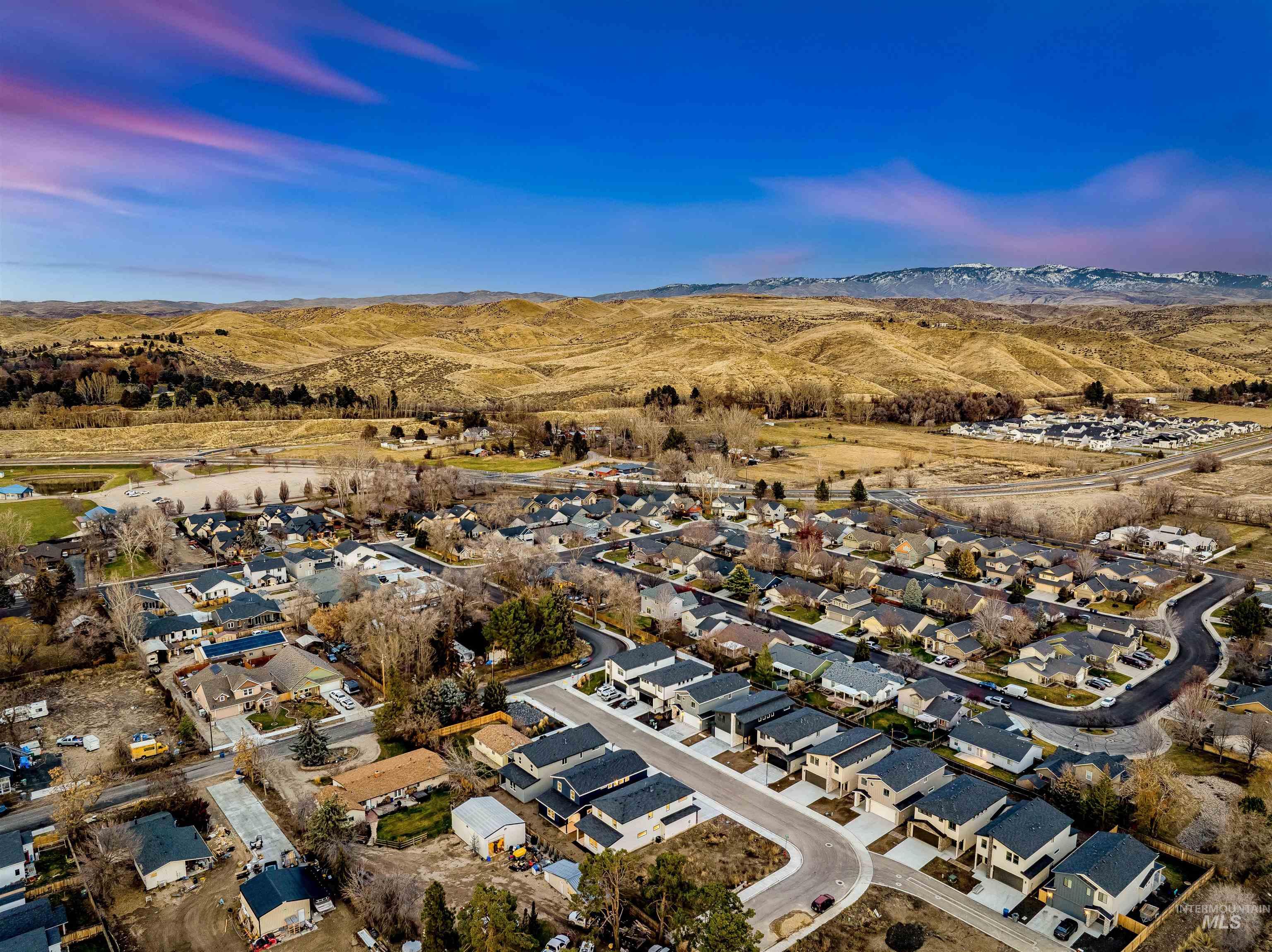 Aerial view of property and surrounding area featuring nearby suburban area and mountains