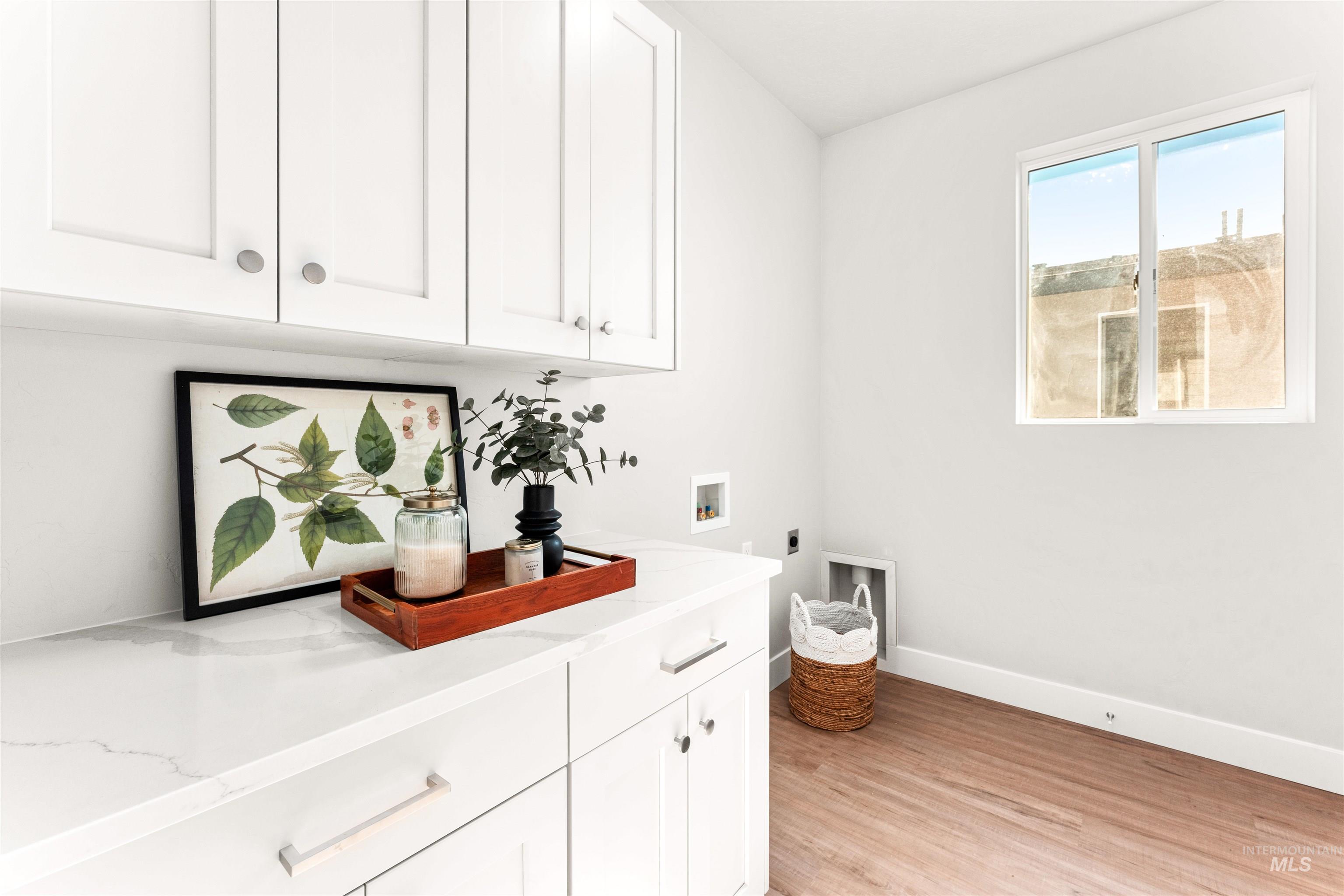 Washroom with hookup for a washing machine, cabinet space, light wood finished floors, and hookup for an electric dryer