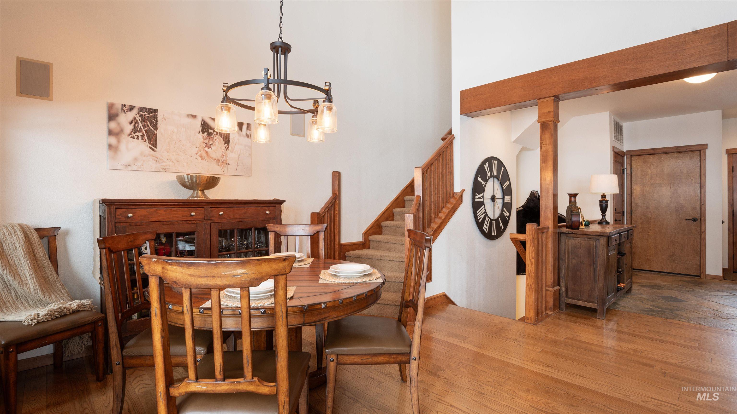 Dining area with hanging lights, wood finished floors, and a high ceiling