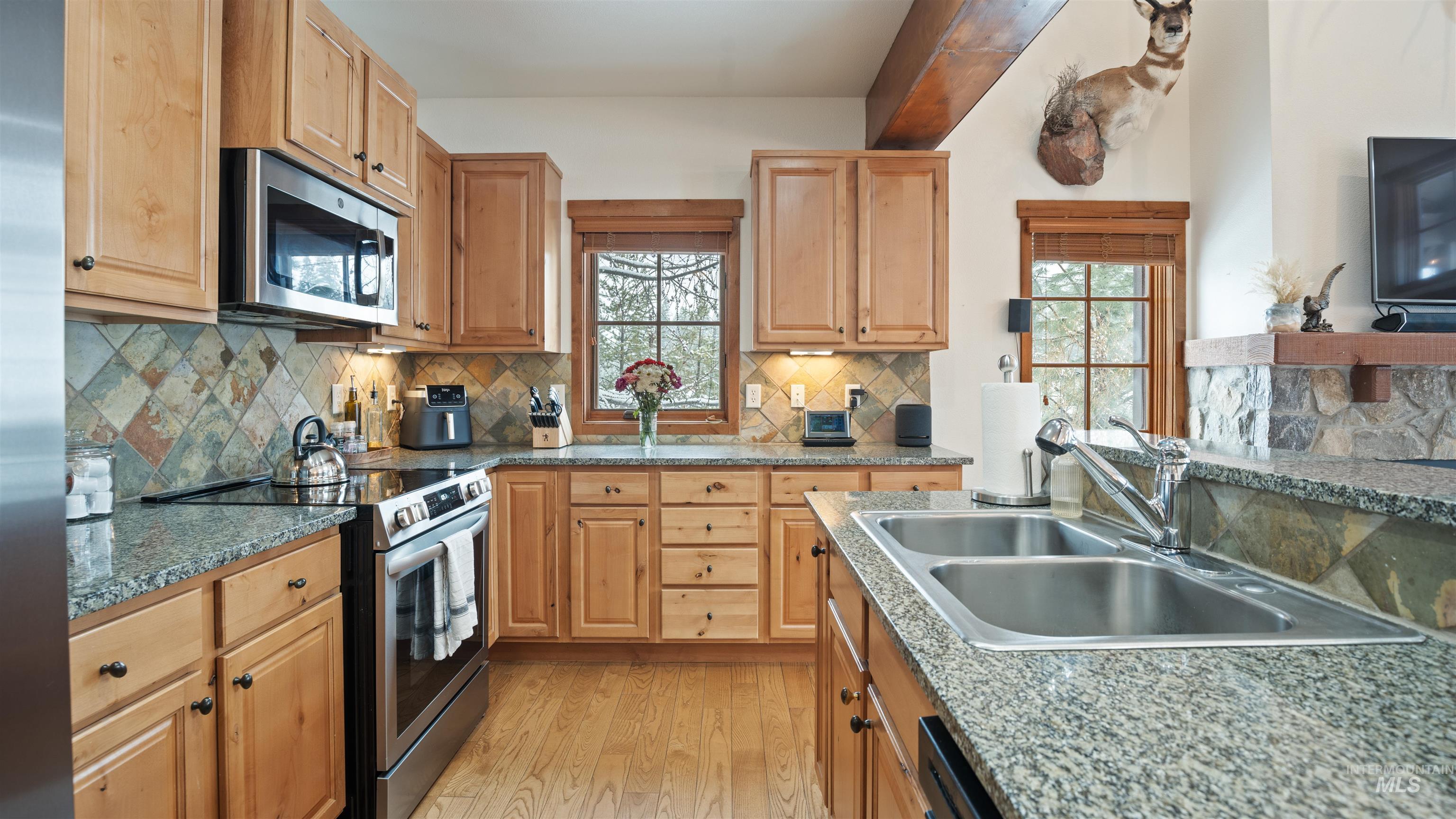 Kitchen with stainless steel appliances, light wood-style flooring, and tasteful backsplash