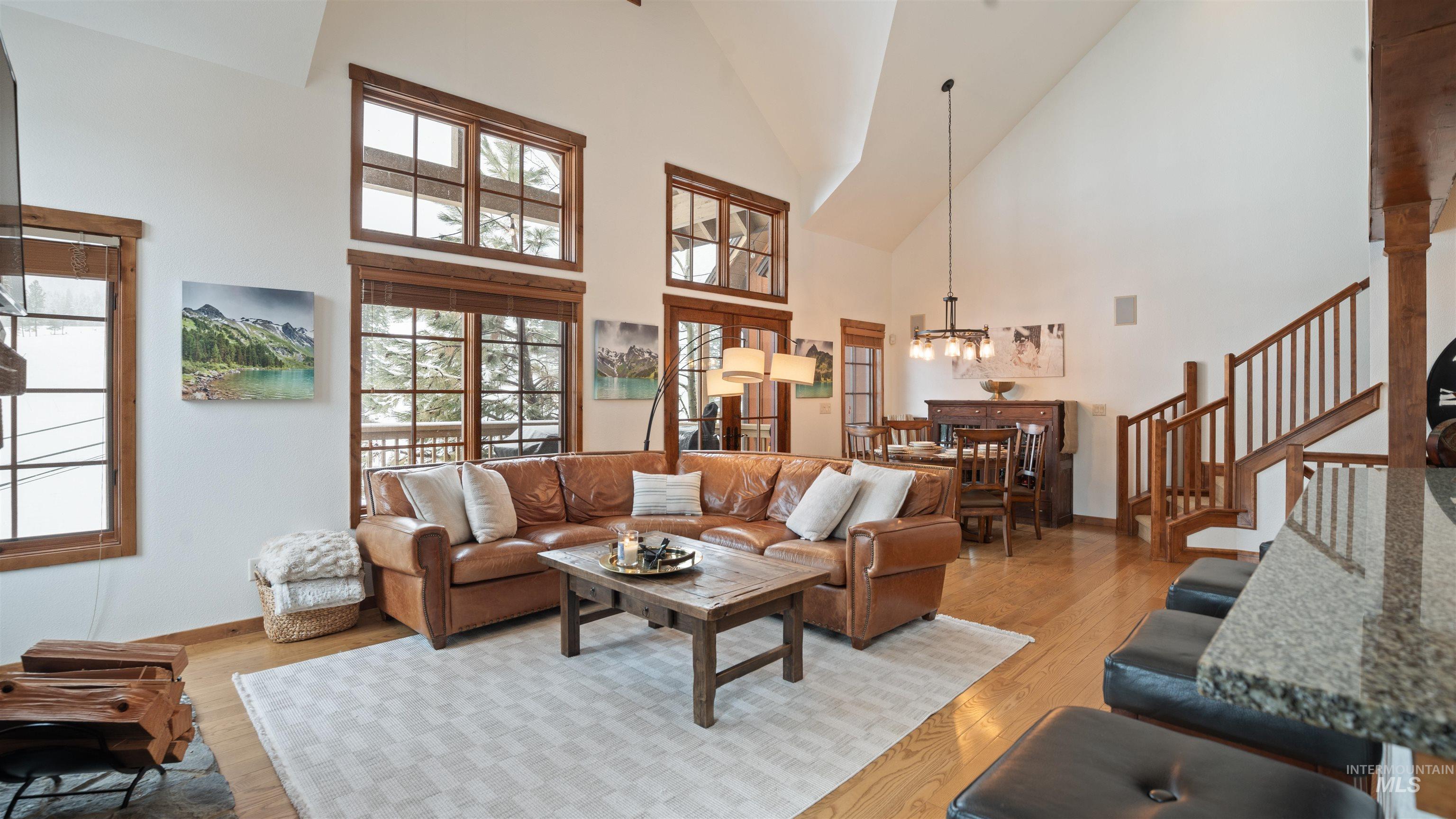 Living area with light wood-style flooring, lofted ceiling, and hanging lights