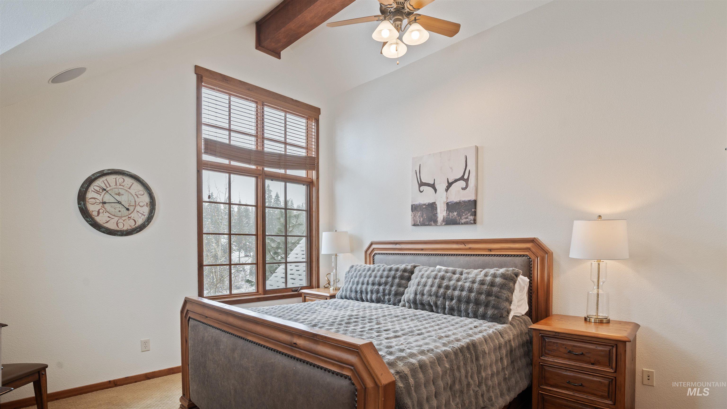 Carpeted bedroom featuring beamed ceiling and a ceiling fan