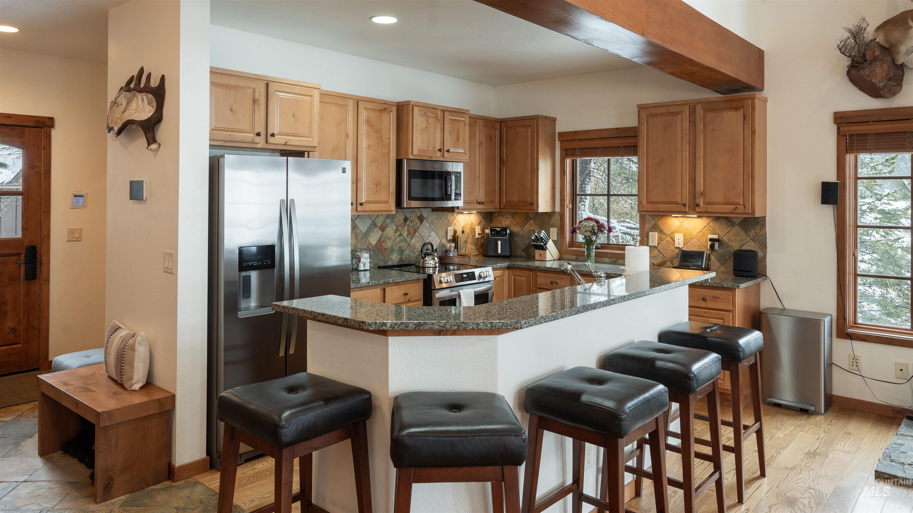 Kitchen featuring stainless steel appliances, a breakfast bar, dark stone counters, backsplash, and recessed lighting