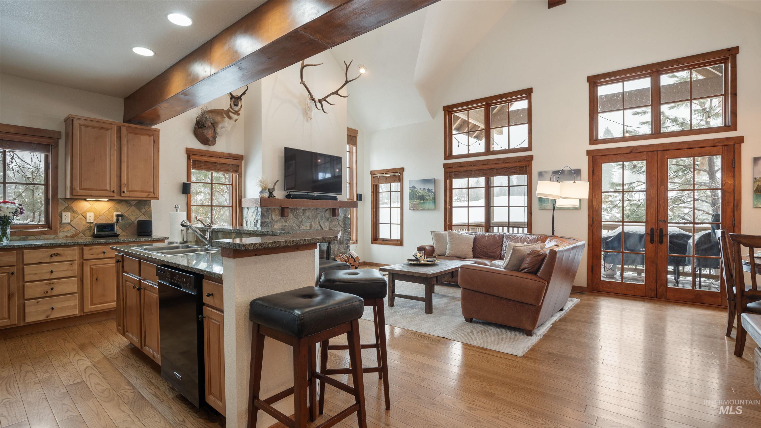 Kitchen with open floor plan, a kitchen bar, light wood-type flooring, vaulted ceiling, and recessed lighting