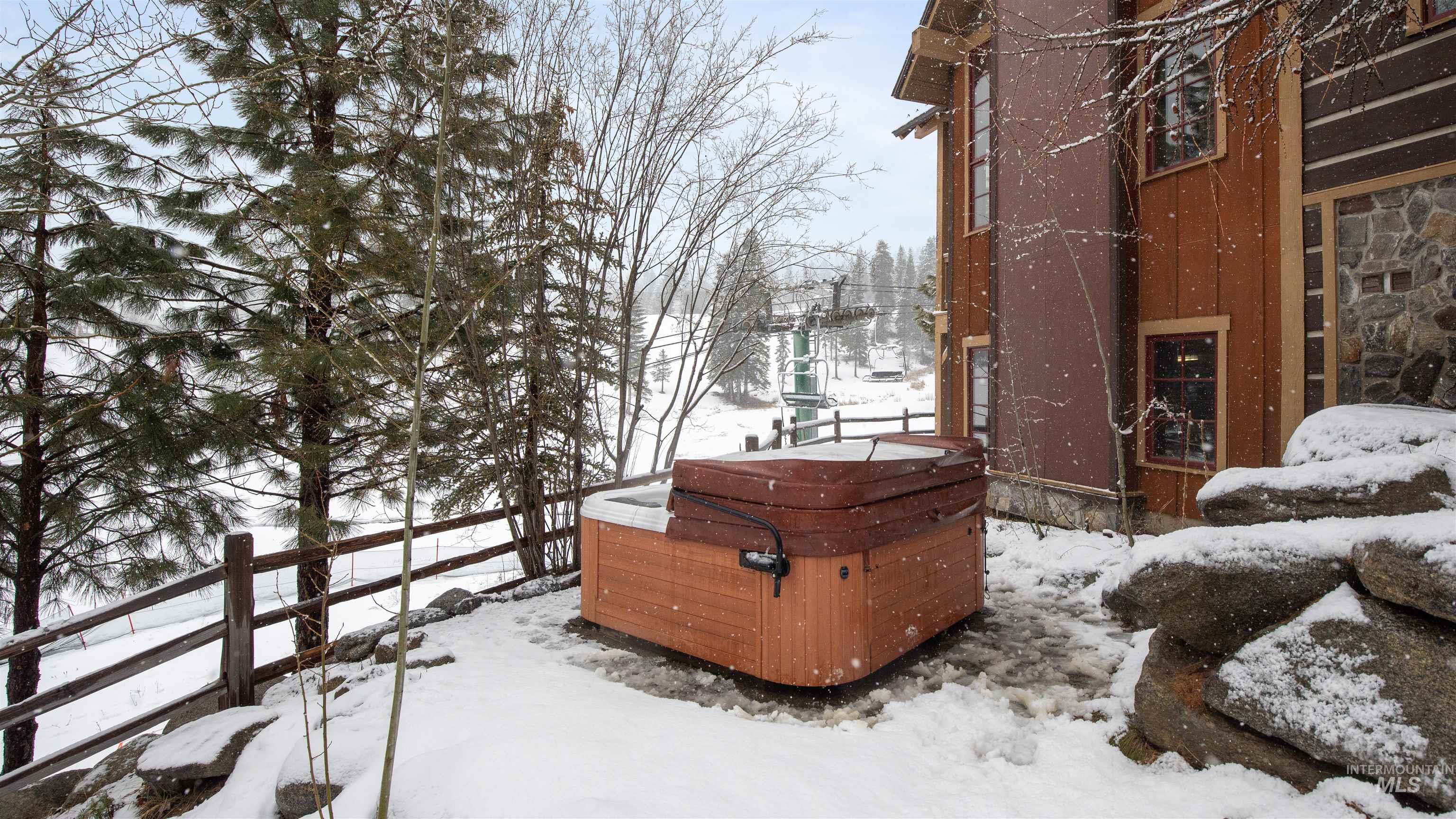 Yard layered in snow featuring a hot tub
