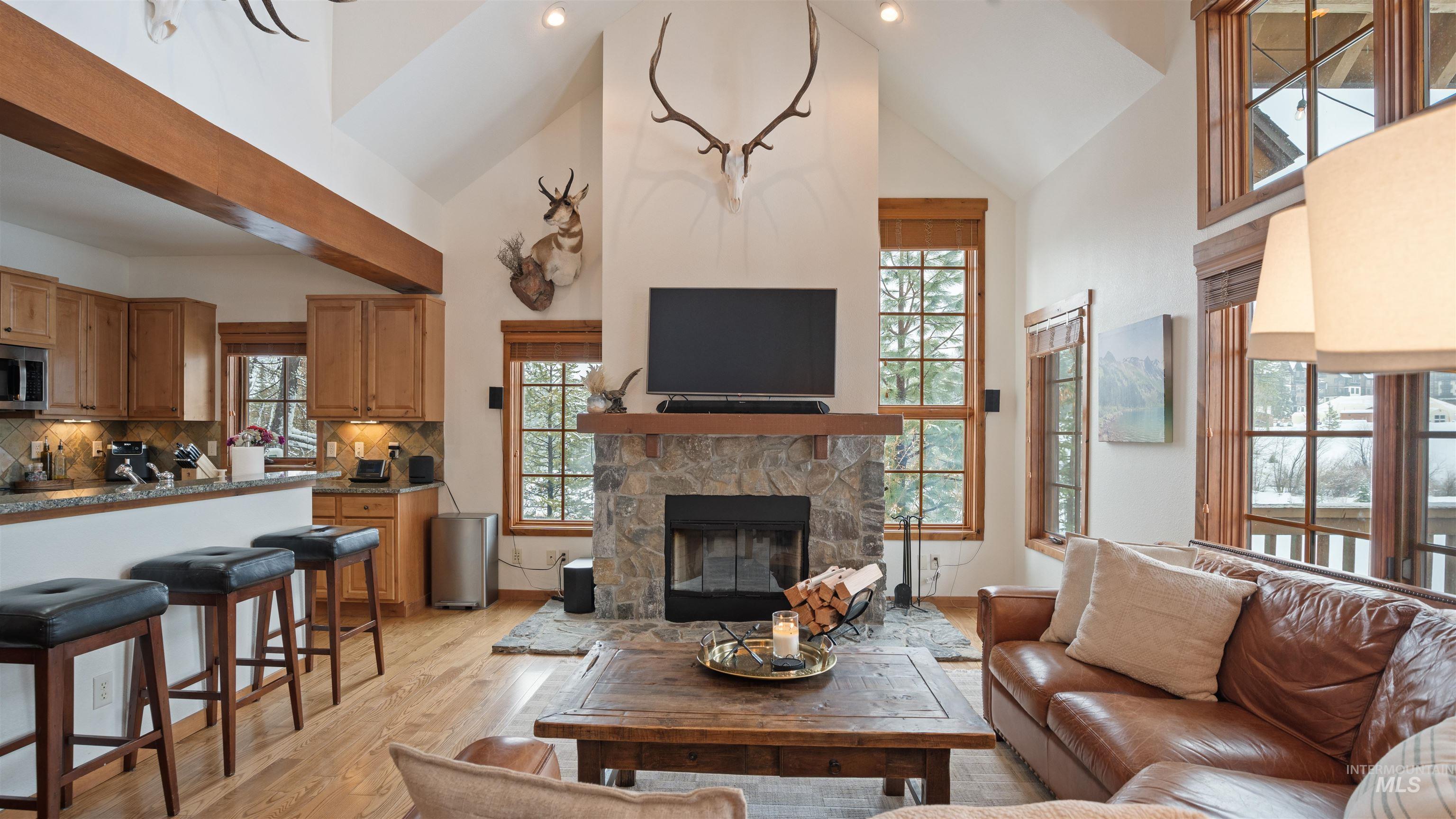 Living room with light wood finished floors, vaulted ceiling, a fireplace, and healthy amount of natural light