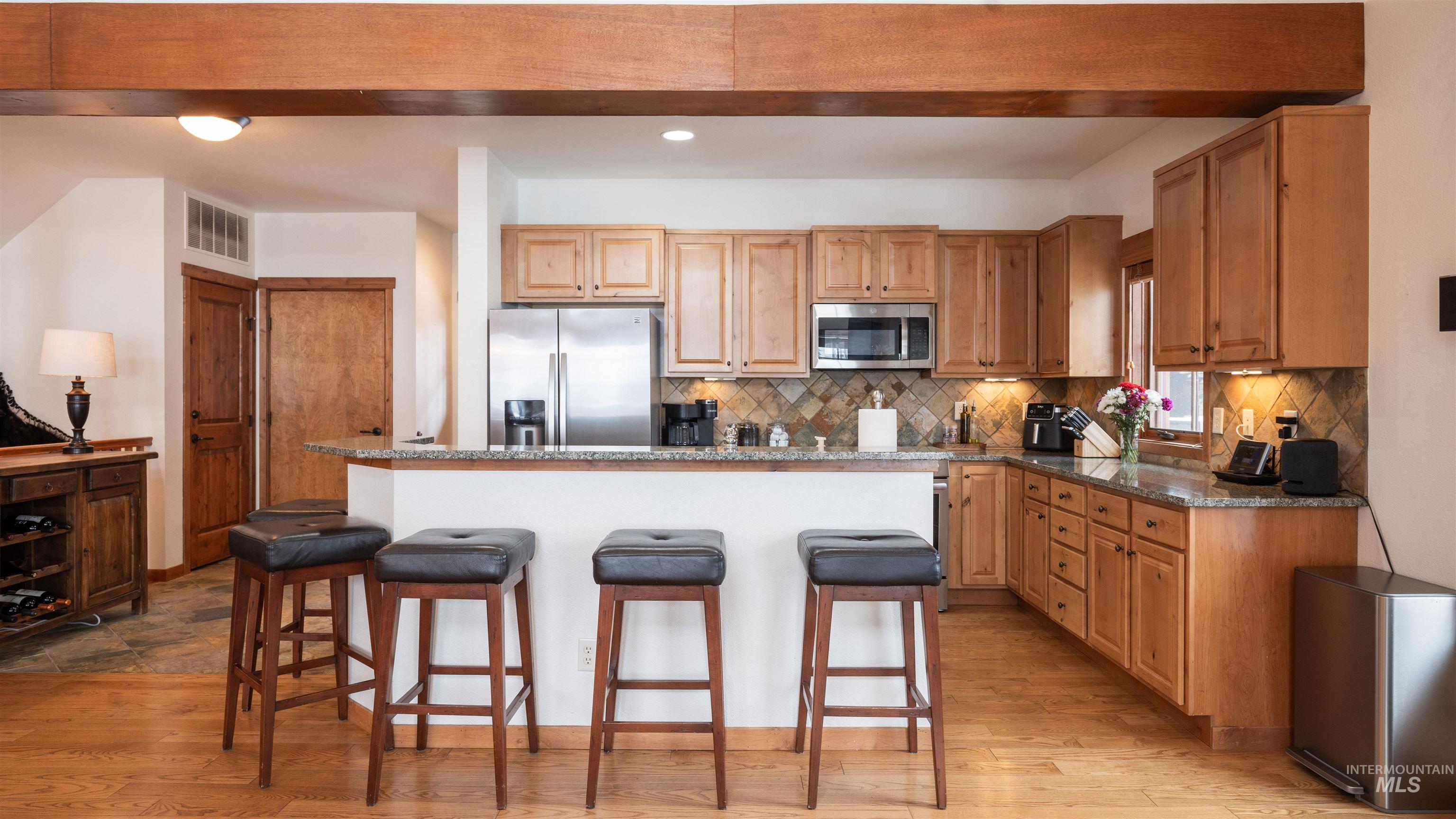 Kitchen with dark stone counters, a kitchen bar, stainless steel appliances, a kitchen island, and recessed lighting