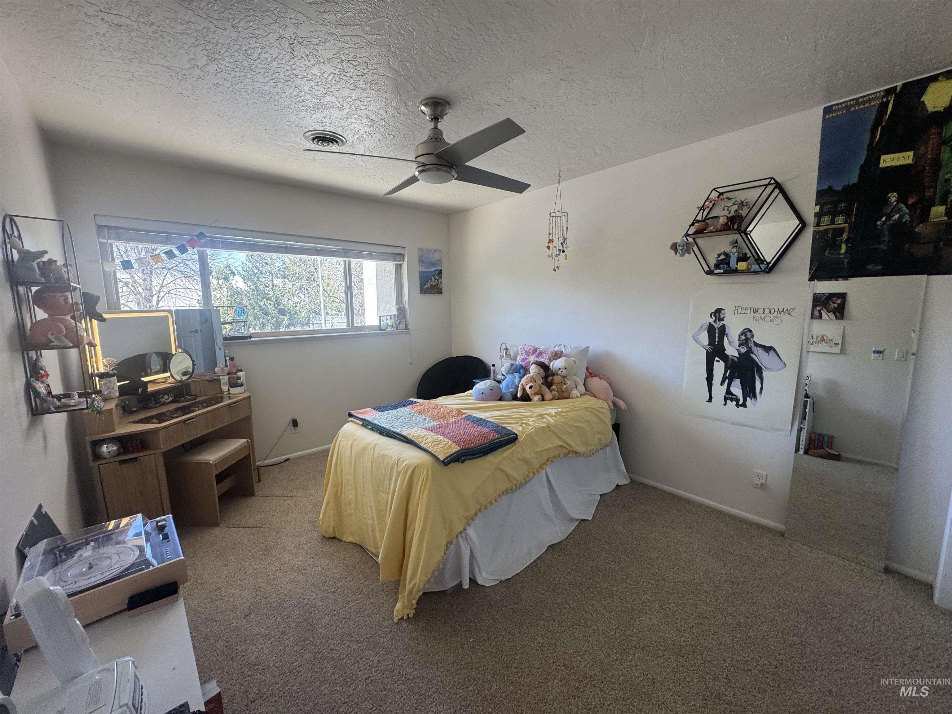 Bedroom with a textured ceiling, light carpet, and ceiling fan