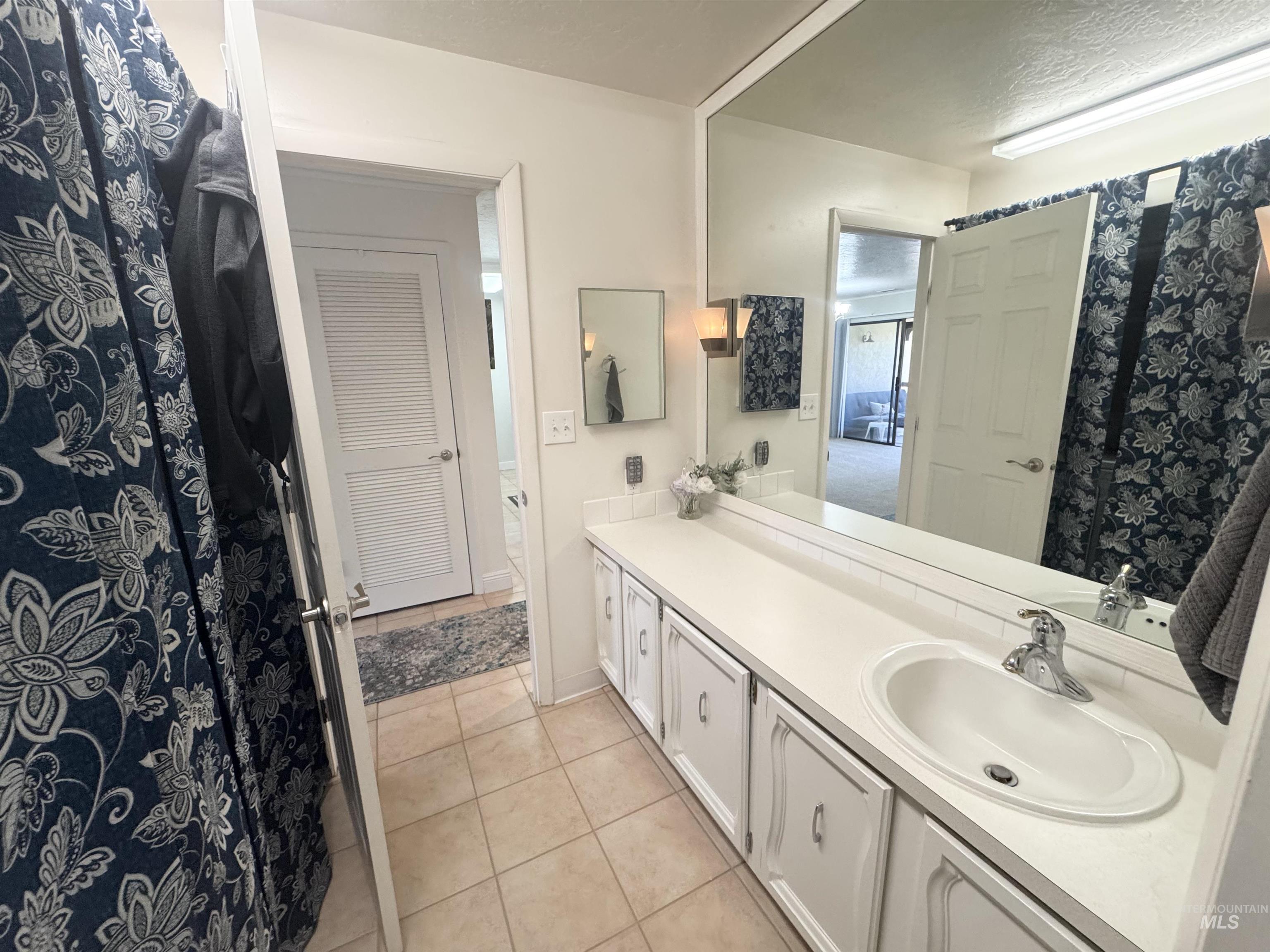 Bathroom with vanity, light tile patterned floors, and curtained shower