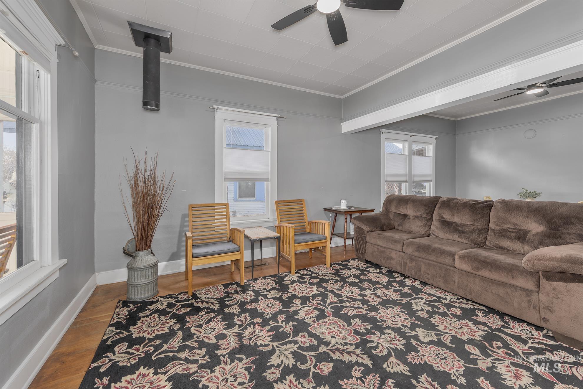 Living room featuring wood finished floors, crown molding, and a ceiling fan