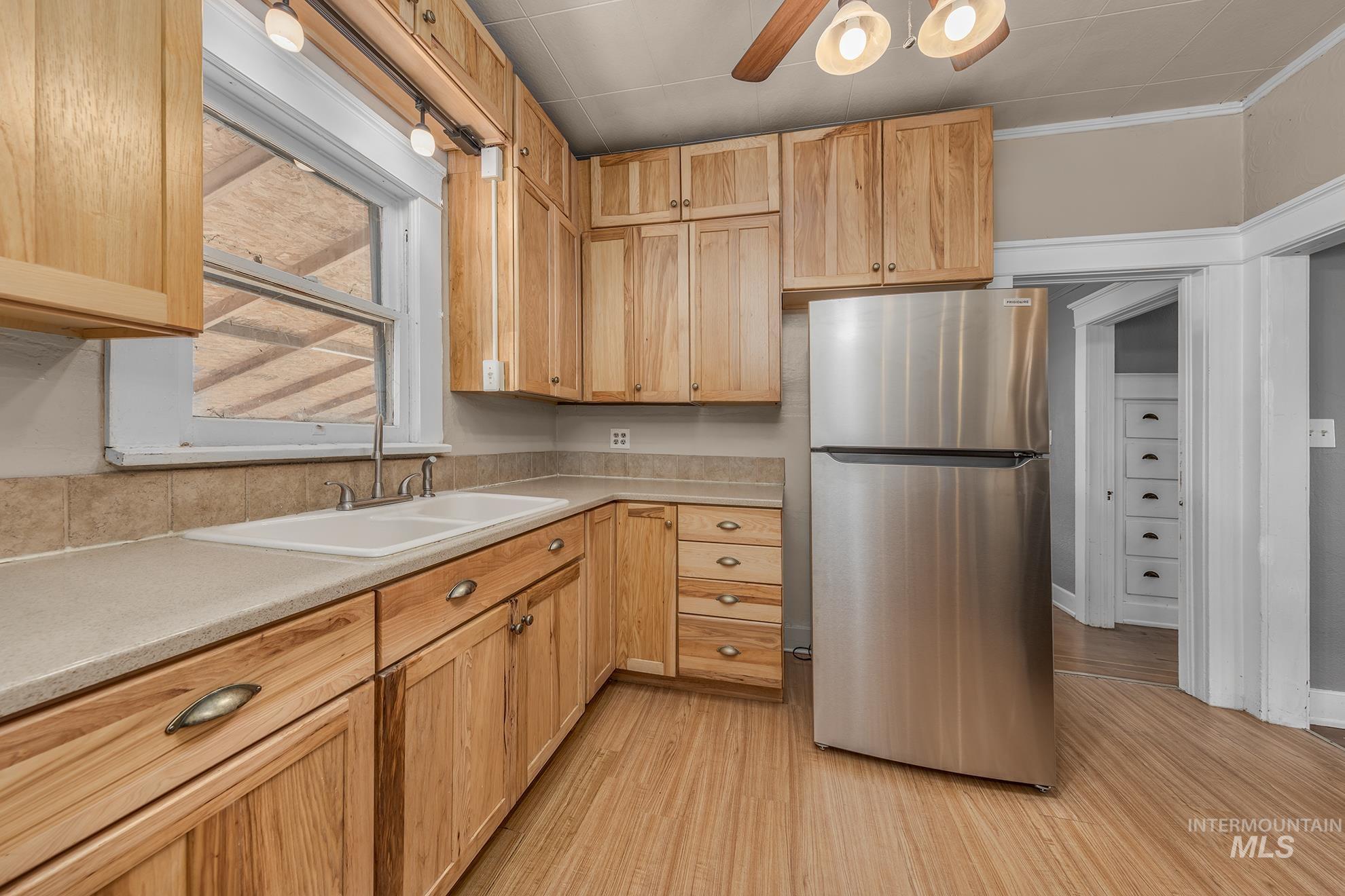 Kitchen featuring freestanding refrigerator, light countertops, light wood-style floors, and a ceiling fan