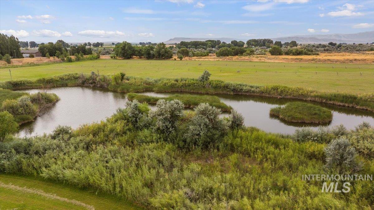 View of community featuring a water view, a view of countryside, a yard, and view of scattered trees