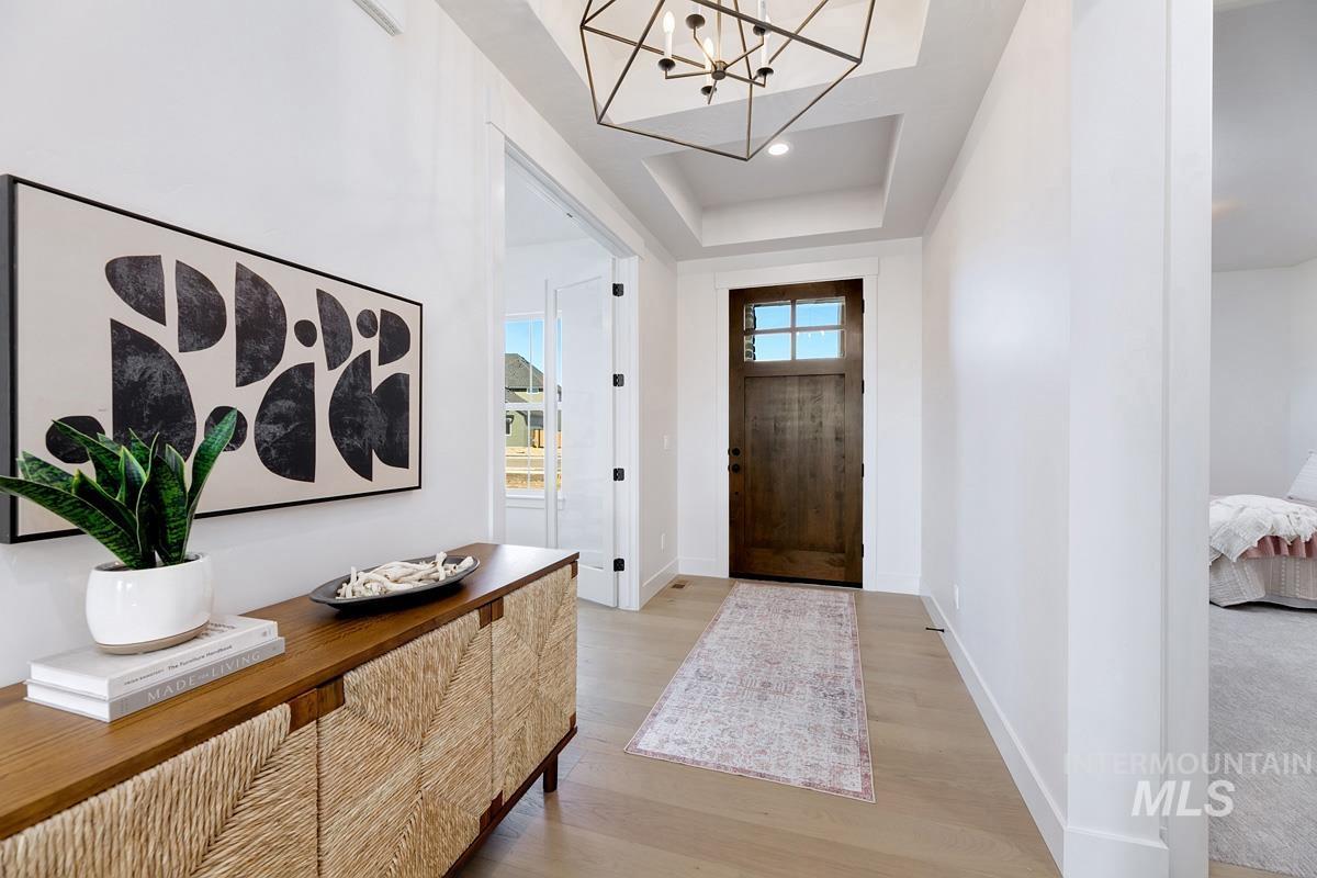Entrance foyer featuring a chandelier, a tray ceiling, and light wood-style flooring