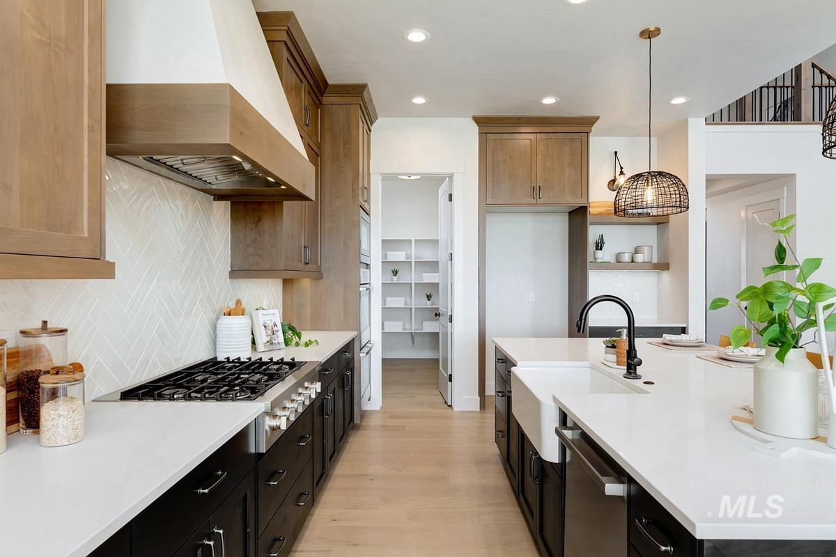 Kitchen with custom range hood, backsplash, hanging light fixtures, light wood-type flooring, and recessed lighting