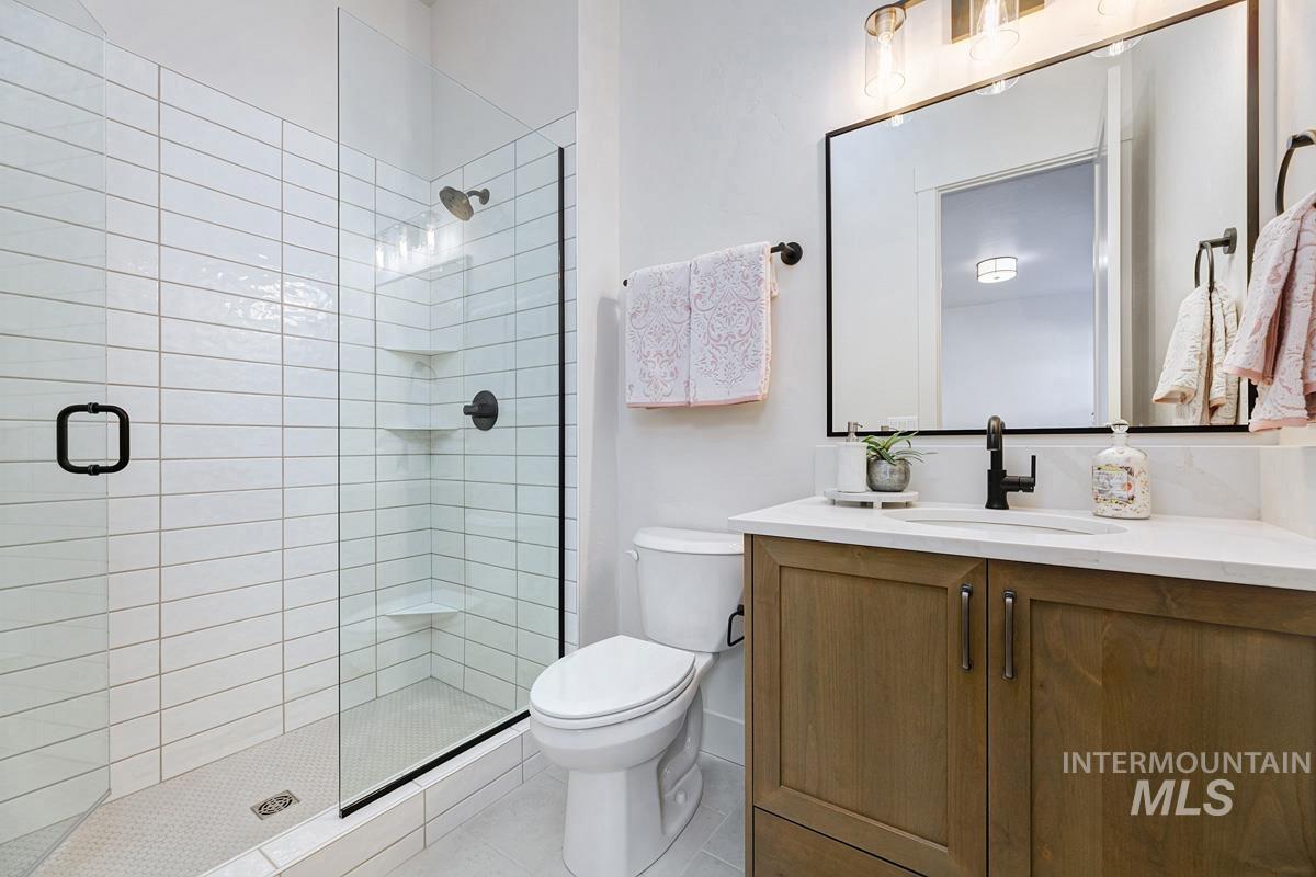 Full bath with vanity, a stall shower, and light tile patterned floors