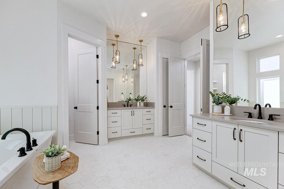 Full bath with a tub to relax in, two vanities, and recessed lighting