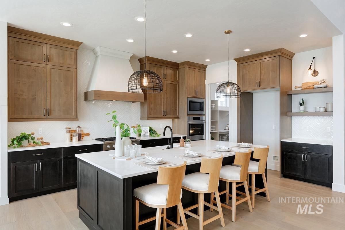 Kitchen featuring open shelves, a breakfast bar area, pendant lighting, custom range hood, and backsplash