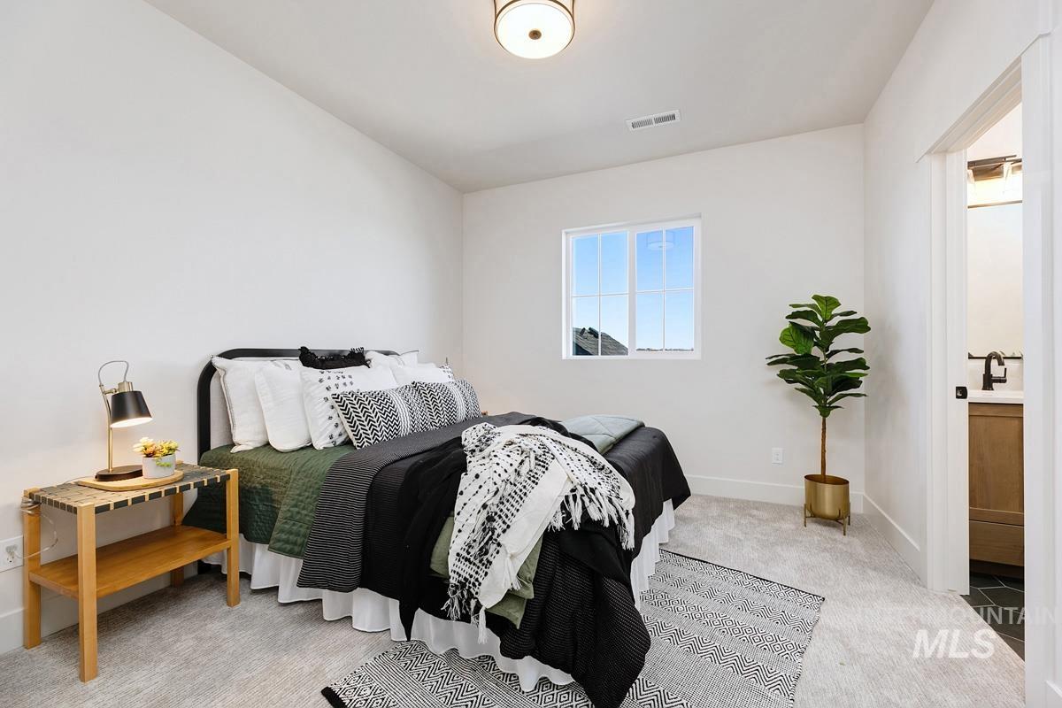 Bedroom with light carpet and connected bathroom