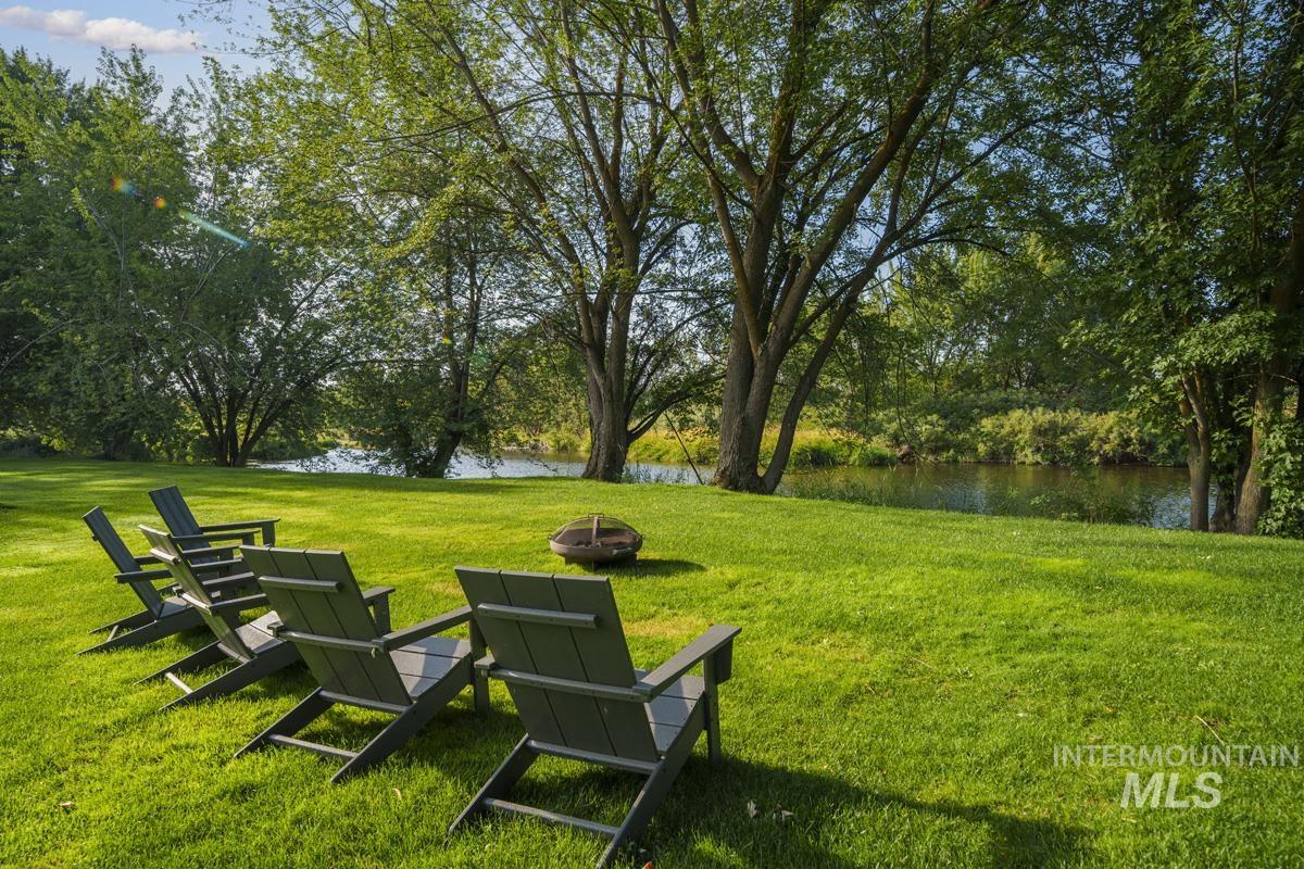 View of community featuring a water view, a yard, and an outdoor fire pit