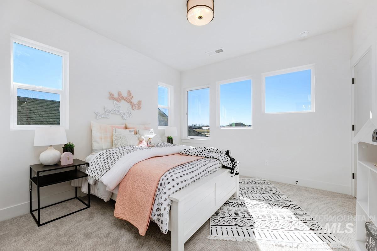 Bedroom featuring light carpet and multiple windows