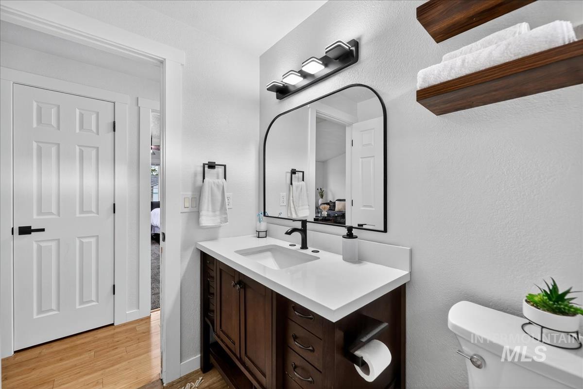 Half bath featuring vanity, light wood-type flooring, and a textured wall