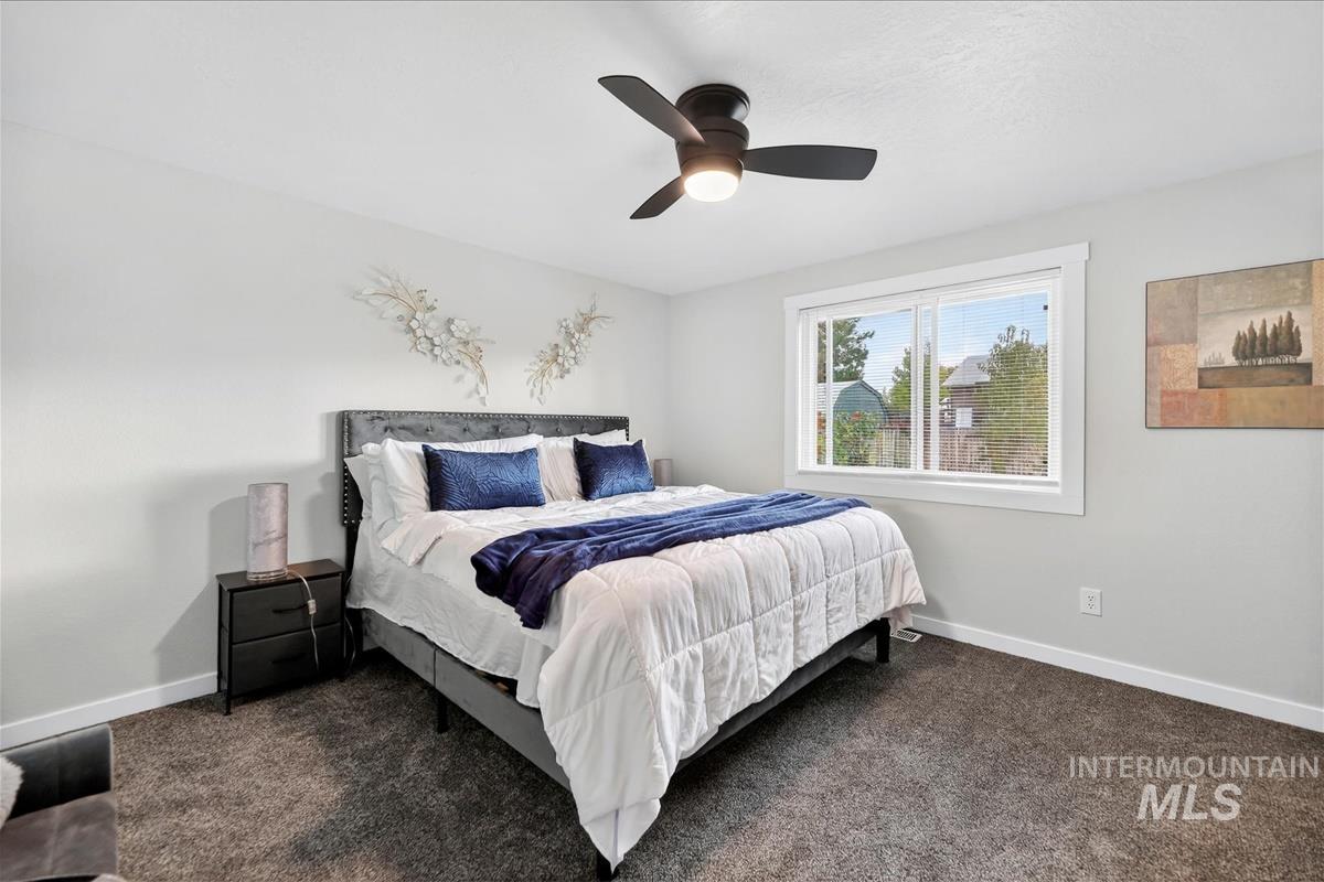 Bedroom with dark colored carpet and a ceiling fan