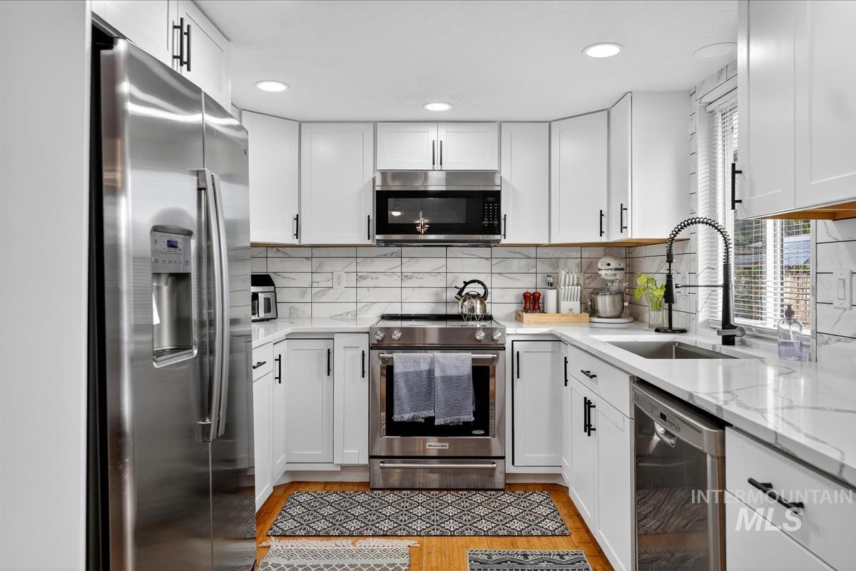Kitchen featuring appliances with stainless steel finishes, white cabinetry, and recessed lighting