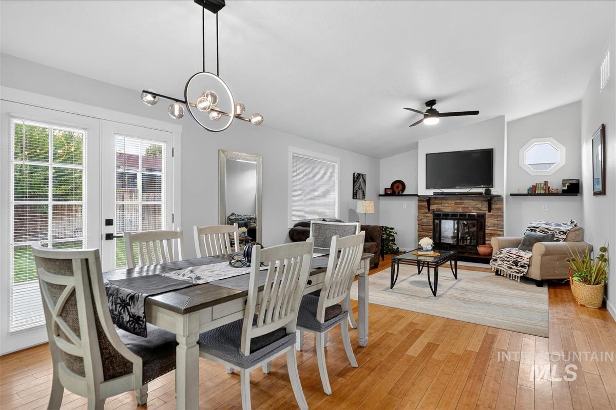 Dining area with light wood-style floors, a fireplace, vaulted ceiling, and a ceiling fan