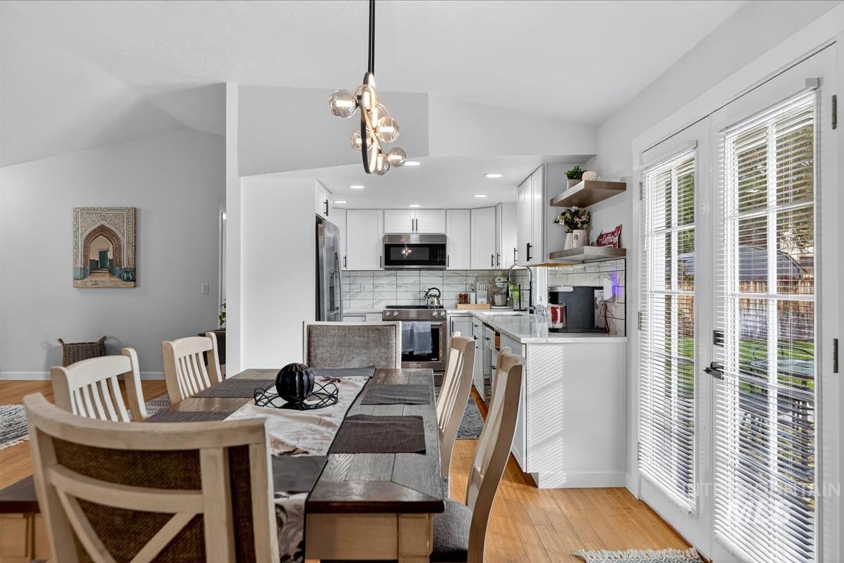 Dining room with vaulted ceiling, light wood-style floors, and recessed lighting