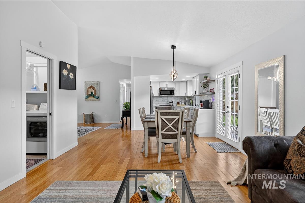 Living area featuring washer / clothes dryer, light wood finished floors, and lofted ceiling