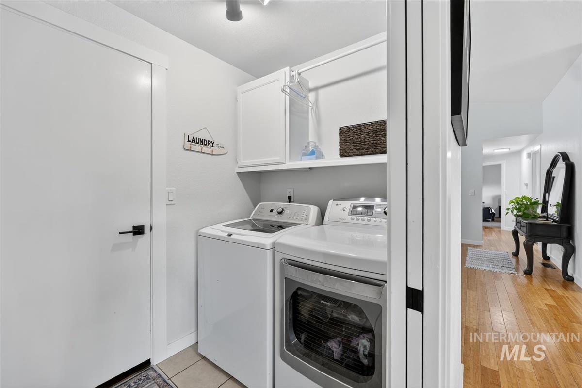 Laundry area featuring separate washer and dryer, light wood-style floors, and cabinet space