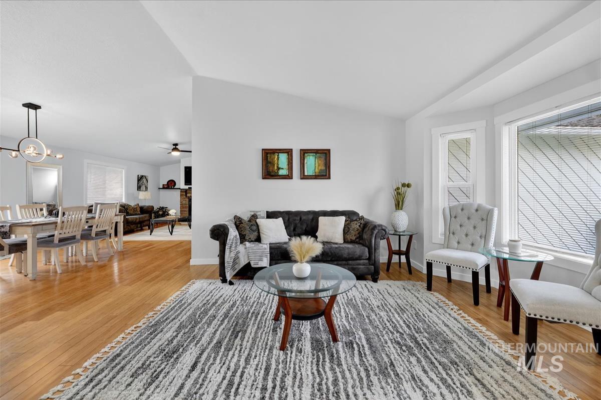 Living area with lofted ceiling, light wood finished floors, a ceiling fan, and a chandelier