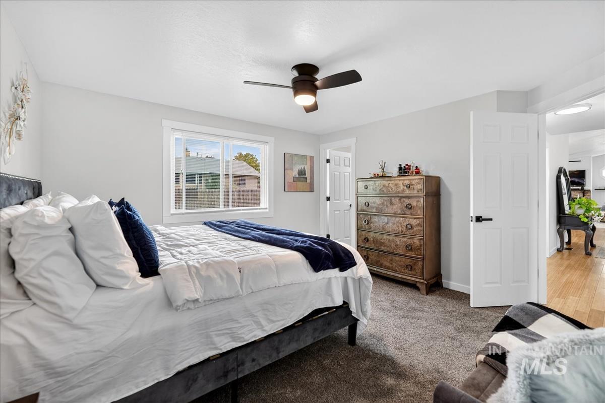 Carpeted bedroom with a ceiling fan and baseboards
