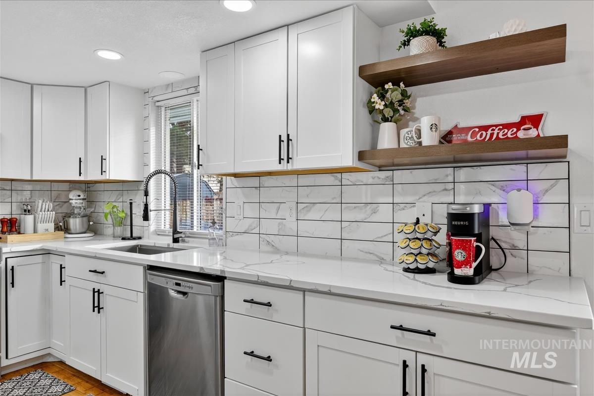 Kitchen featuring open shelves, white cabinets, stainless steel dishwasher, light stone countertops, and recessed lighting