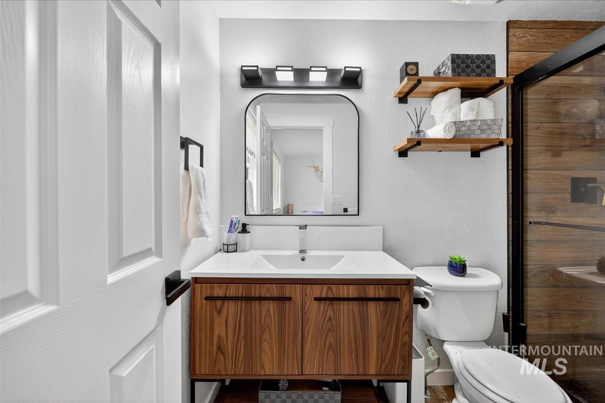 Bathroom with vanity, a stall shower, and a textured wall