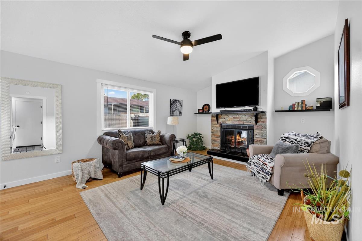 Living area with vaulted ceiling, light wood-style floors, a fireplace, and a ceiling fan