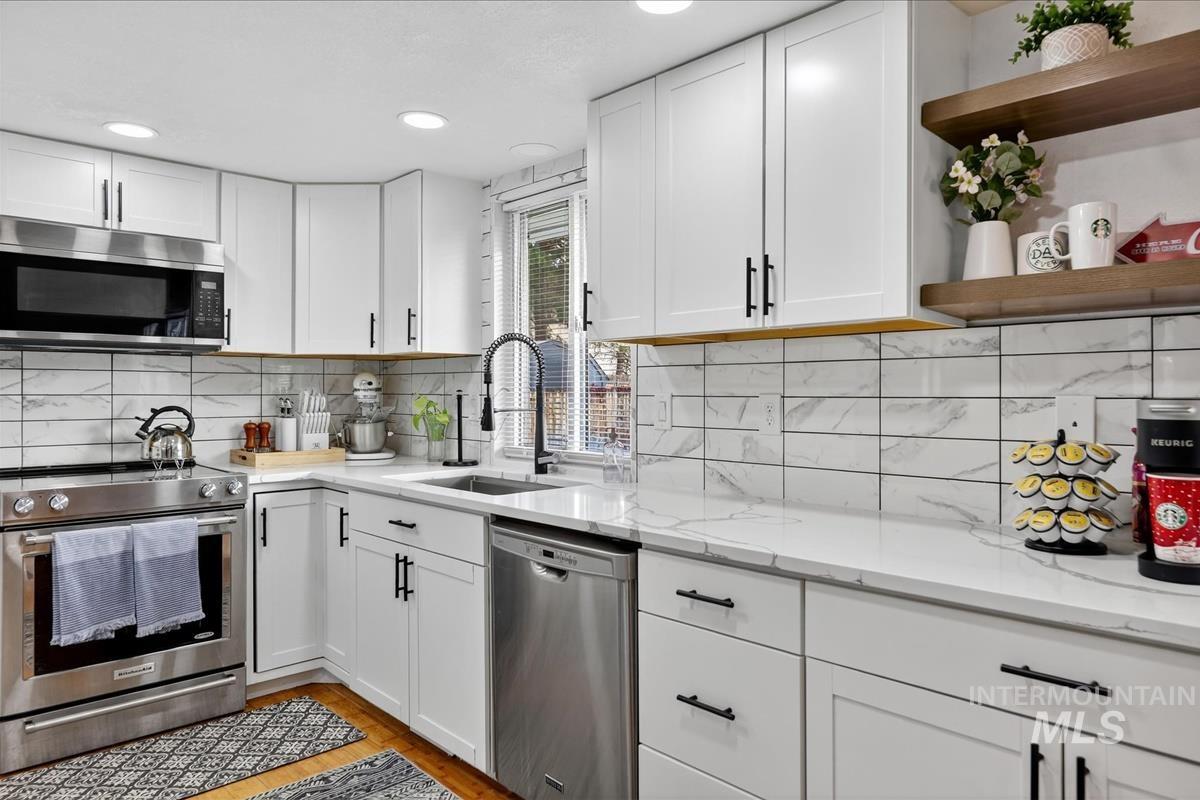 Kitchen with open shelves, white cabinetry, stainless steel appliances, light stone countertops, and recessed lighting