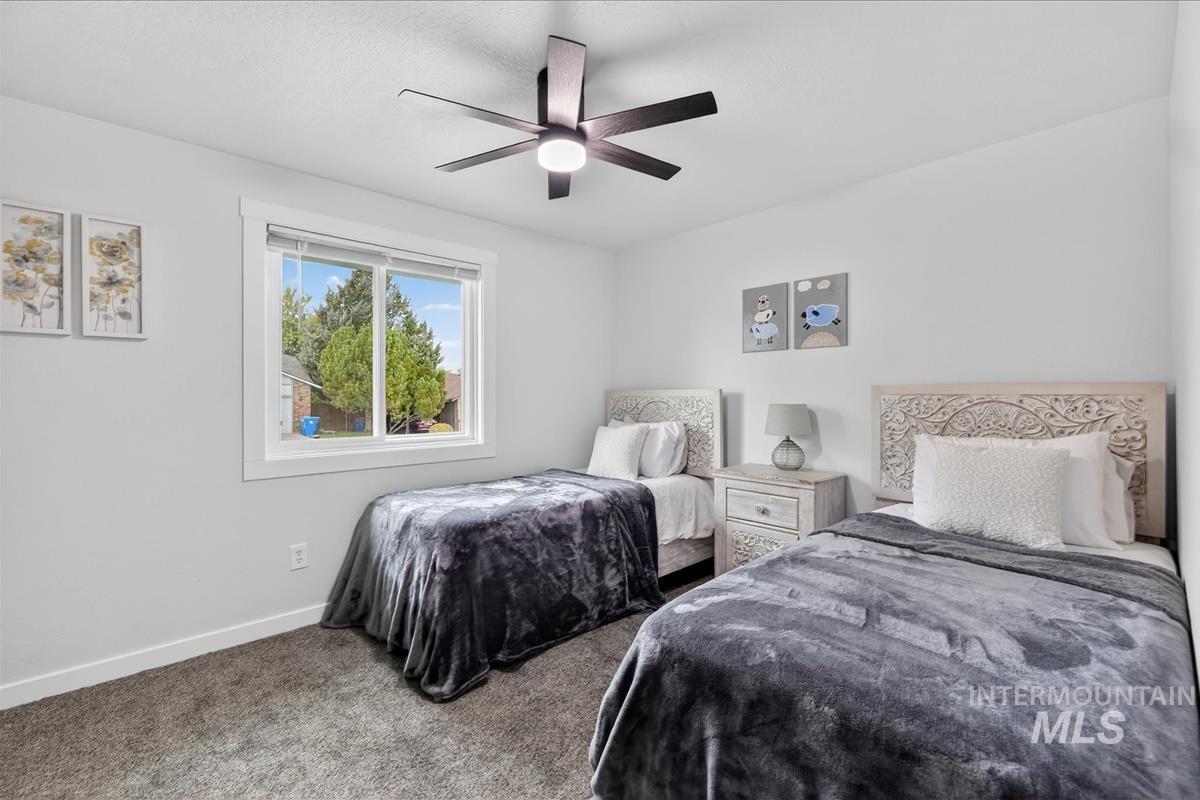 Carpeted bedroom with ceiling fan and baseboards