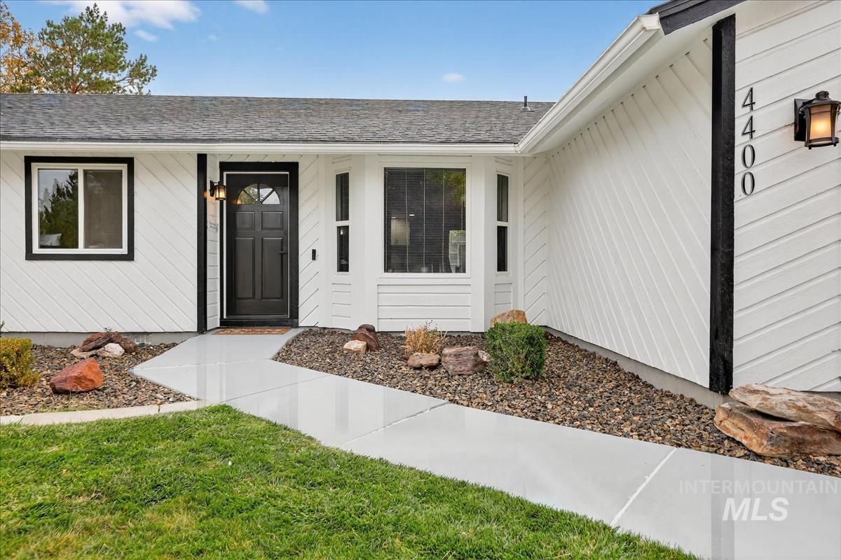 Doorway to property with a yard and a shingled roof