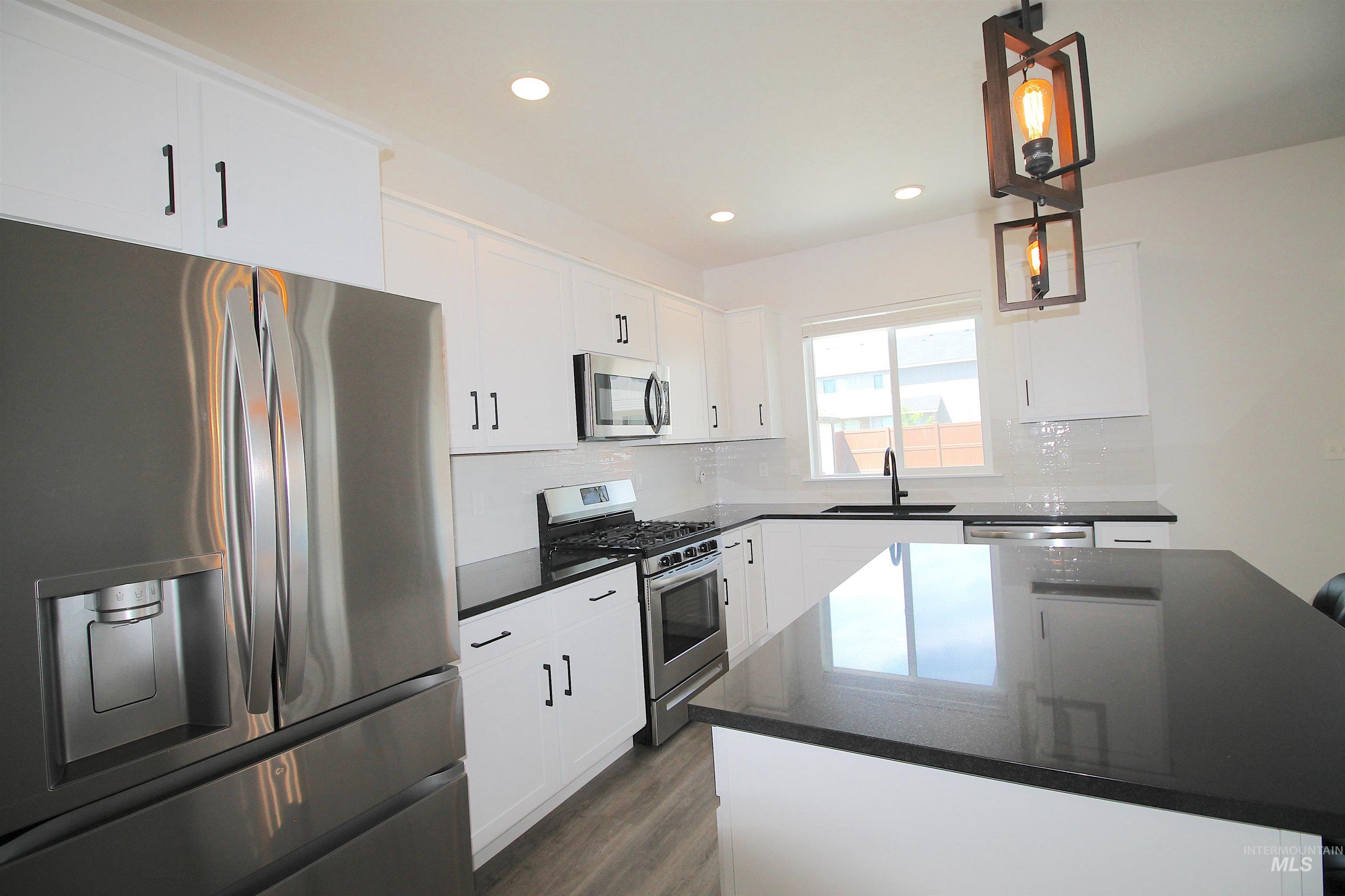 Modern kitchen featuring white cabinetry, dark countertops, and stainless steel appliances